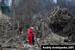 Медик заспокоює жінку посеред руїн знищених Росією приватних будинків у Запоріжжі. 22 березня 2024 року