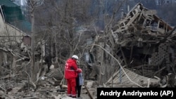 Медработник успокаивает женщину среди руин домов в Запорожье. Последствия российской ракетной атаки 22 марта 2024 года