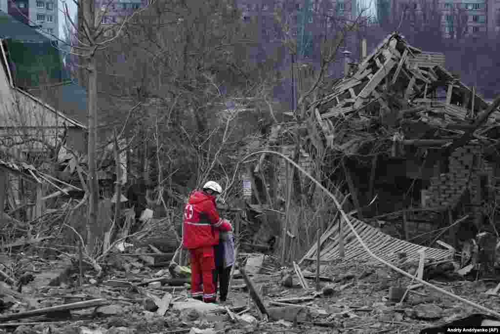 Медпрацівник заспокоює жінку посеред руїн будинків у Запоріжжі. Наслідки російської ракетної атаки. 22 березня 2024 року