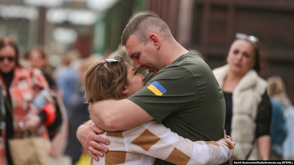 Derisa disa ushtarë japin përqafime lamtumire, të tjerë, si ky, hidhen në përqafime mirëseardhjeje të partnereve të tyre.  