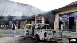 A man looks at charred shops and a vehicle torched by the BLA militants in Bolan district, Balochistan on January 30.