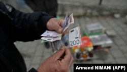 Ulični prodavac drži dinare u Grančanici u centralnom delu Kosova, 1. marta 2024.