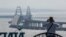 CRIMEA -- A photograph taken on October 8, 2022 shows a man taking a picture of the bridge that links Crimea to Russia 