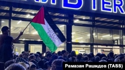 Натовп під терміналом аеропорту у Махачкалі скандує антиізраїльські гасла. Учасник тримає прапор Палестини. Дагестан, 28 жовтня 2023 року