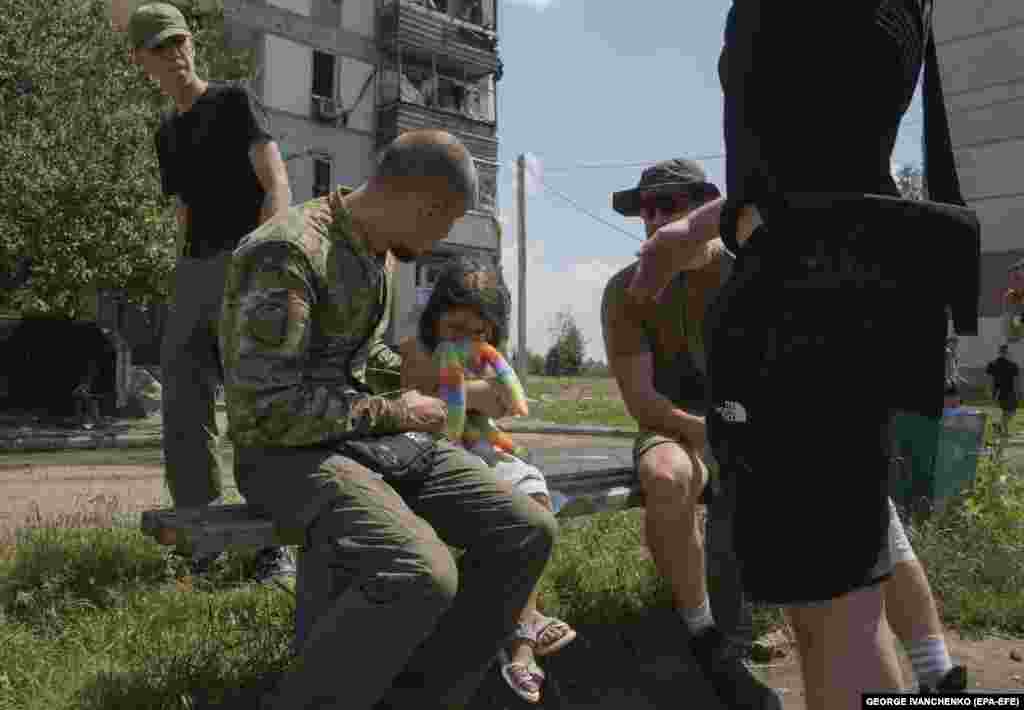 Чоловіки заспокоюють дівчинку, яка плаче після російського ракетного удару по житловій забудові у Первомайському. 4 липня 2023 року &nbsp;