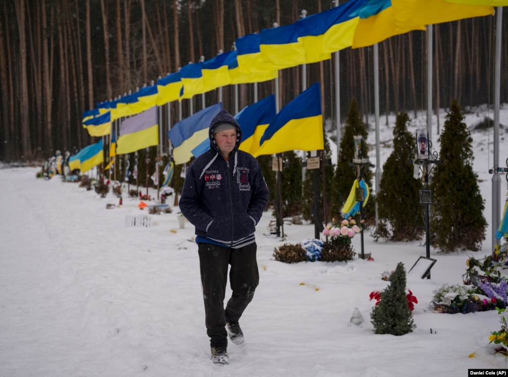 Një burrë ec pranë Shtegut të Heronjve në një varrezë në Irpin afër Kievit, në shkurt 2023.