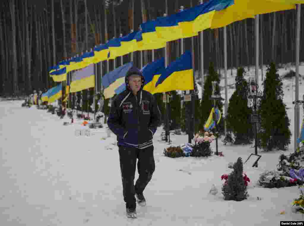 An undertaker walks past the Alley of Heroes at a cemetery in Irpin, near Kyiv, in February 2023.&nbsp;