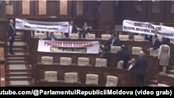 Депутати от проруския Блок на комунистите и социалистите разпъват протестни плакати в пленарната зала.