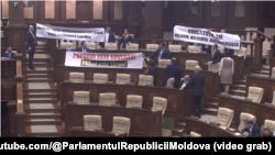 Parlamentari din opoziția socialistă și comunistă au protestat afișând pancarte în apărarea limbii „moldovenești”