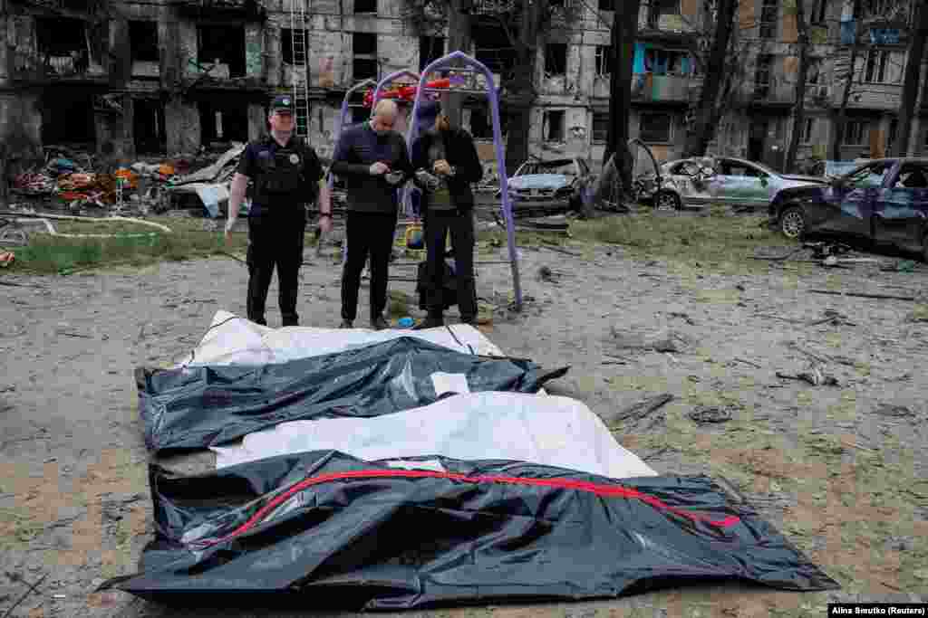 The covered bodies of four people who died in the attack are seen near the burned-out residential building.