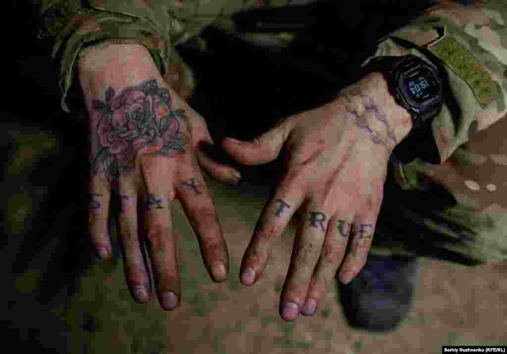 A soldier shows off his tattoos while resting in his dugout. &nbsp;