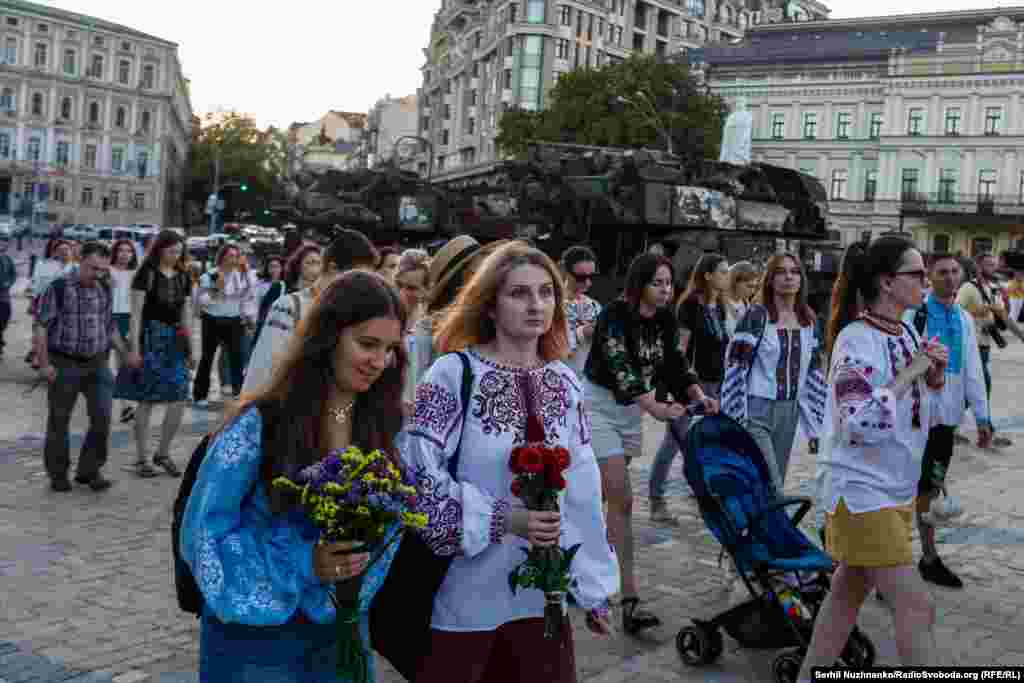 În timpul evenimentului memorial, oamenii trec pe lângă vehiculele militare rusești distruse expuse la Kiev