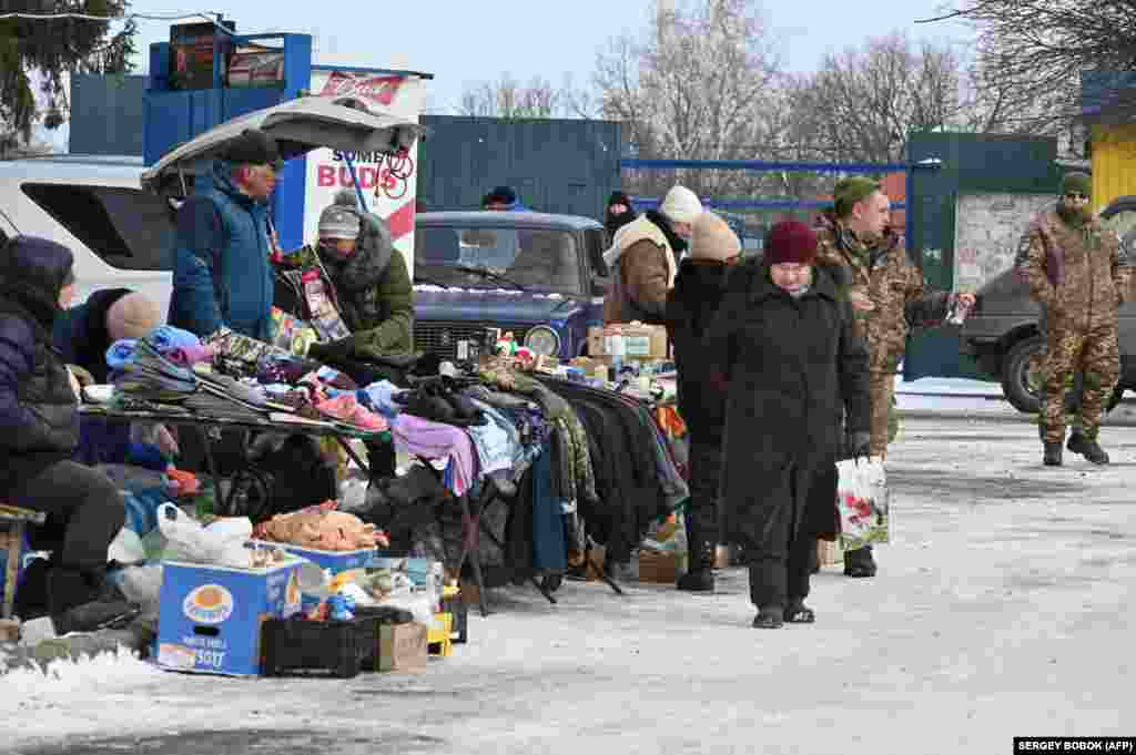 Civilii și soldații fac cumpărături într-o piață în aer liber din Kupiansk, pe 13 februarie. Olha, în vârstă de 62 de ani, care a refuzat să își dea numele de familie, vrea, de asemenea, să părăsească orașul, dar este nevoită să rămână și să aibă grijă de fiul ei cu handicap, în vârstă de 37 de ani. De asemenea, nu au unde să se ducă, a adăugat ea. &bdquo;Sunt explozii în fiecare zi, așa că ne este foarte frică&rdquo;, a spus ea. &bdquo;Trebuie să ne ascundem în pivniță. Toată lumea vorbește despre un nou atac rusesc&rdquo;.