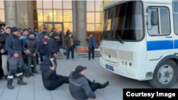 Рабочие нефтяники перед автобусом с задержанными земляками во время разгона полицией мирной демонстрации. Астана, 11 апреля 2023 года