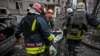 Рятувальники виносять поранену жінку з пошкодженого ракетним ударом будинку, Київ, 2 січня 2024 року
