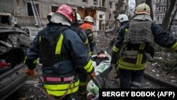 Рятувальники виносять поранену жінку з пошкодженого ракетним ударом будинку, Київ, 2 січня 2024 року