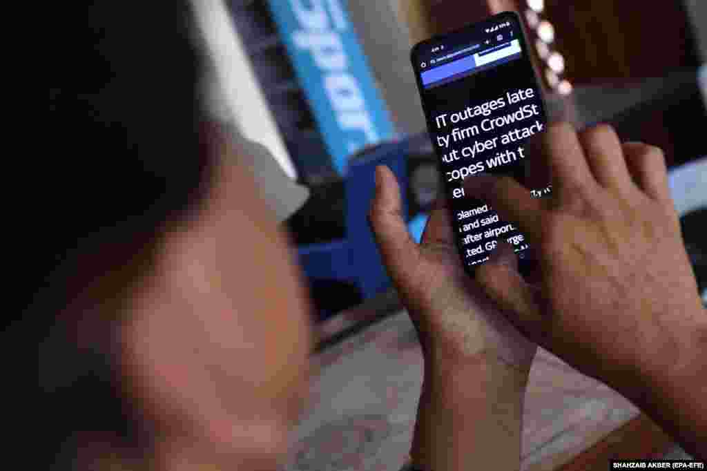 A man reads news of Microsoft&#39;s global outage on a mobile phone in Karachi, Pakistan. &nbsp;