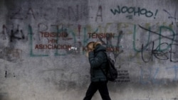 Një grua kalon pranë një ndërtese në Prishtinë ku është shkruar "Tension për Asociacion". Fotografi ilustruese nga arkivi. 