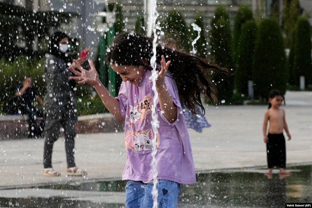 Una ragazza iraniana si rinfresca a una fontana artesiana durante il caldo torrido di Teheran.