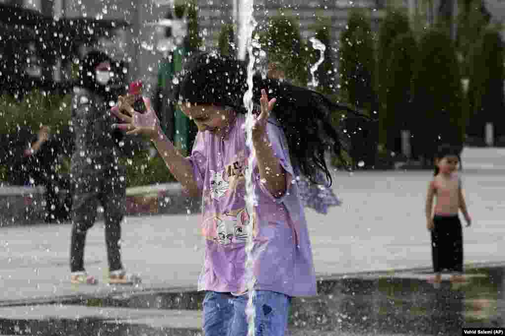 An Iranian girl enjoys a water fountain amid soaring temperatures in Tehran.