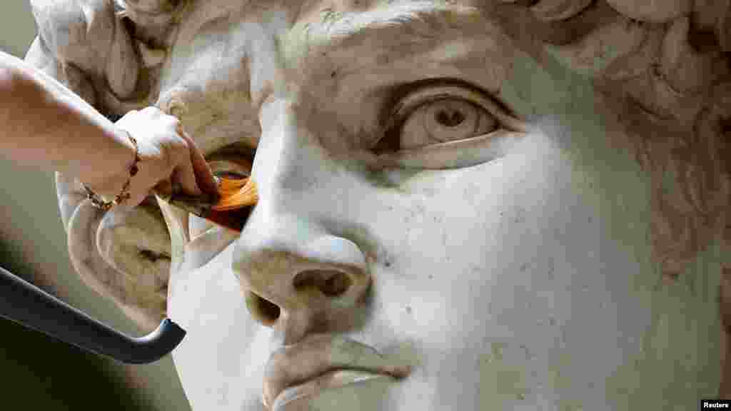 Eleonora Pucci restaurátor hátizsákos porszívóval és műszálas kefével tisztítja a port és a törmeléket Michelangelo Dávid-szobráról a Galleria dell&#39;Accademia múzeumban Firenzében, 2023. szeptember 25-én