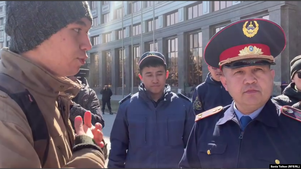Азамат Садыков, офицер полиции (справа), обращается к волонтёрам, которые организовали еду и питье для протестующих. Астана, 11 апреля 2023 года