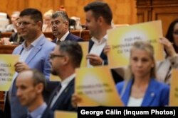 Marcel CIolacu a fost criticat de Opoziție pentru noul pachet de măsuri fiscal-bugetare. În imagine, parlamentari AUR care țin pancarte, în timpul discursului premierului.