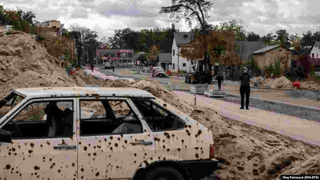 Újjáépítenek egy megrongálódott utat Irpinyben október 23-án. A szétlőtt autó emlékeztet a Kijev külvárosában tavaly zajló heves harcokra. Az összecsapás 2022. február 27-től 2022. március 28-ig tartott, és azzal ért véget, hogy az ukrán csapatok visszafoglalták a várost
