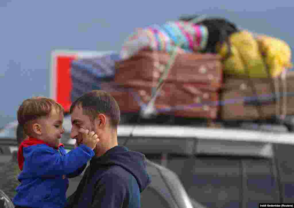 A refugee from Azerbaijan&#39;s breakaway Nagorno-Karabakh region holds a child while standing next to a car upon their arrival in the Armenian border village of Kornidzor on September 26.