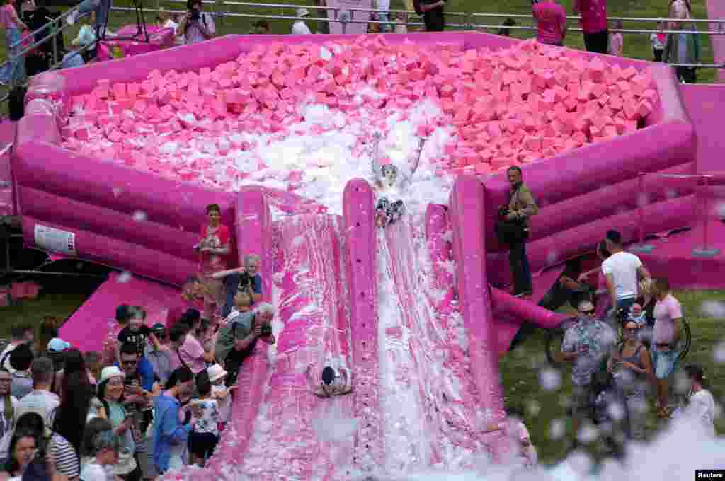 Ljudi klize niz ružičasti tobogan u improviziranu zdjelu na naduvavanje hladne ružičaste supe. Prizor zabilježen na festivalu Pink Soup u Vilniusu, Litvanija, 1. juna 2024.