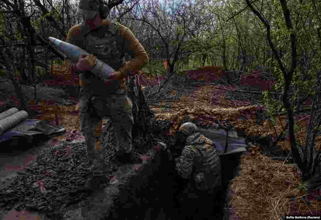 A Ukrainian soldier ferries shells to a waiting D30 howitzer.