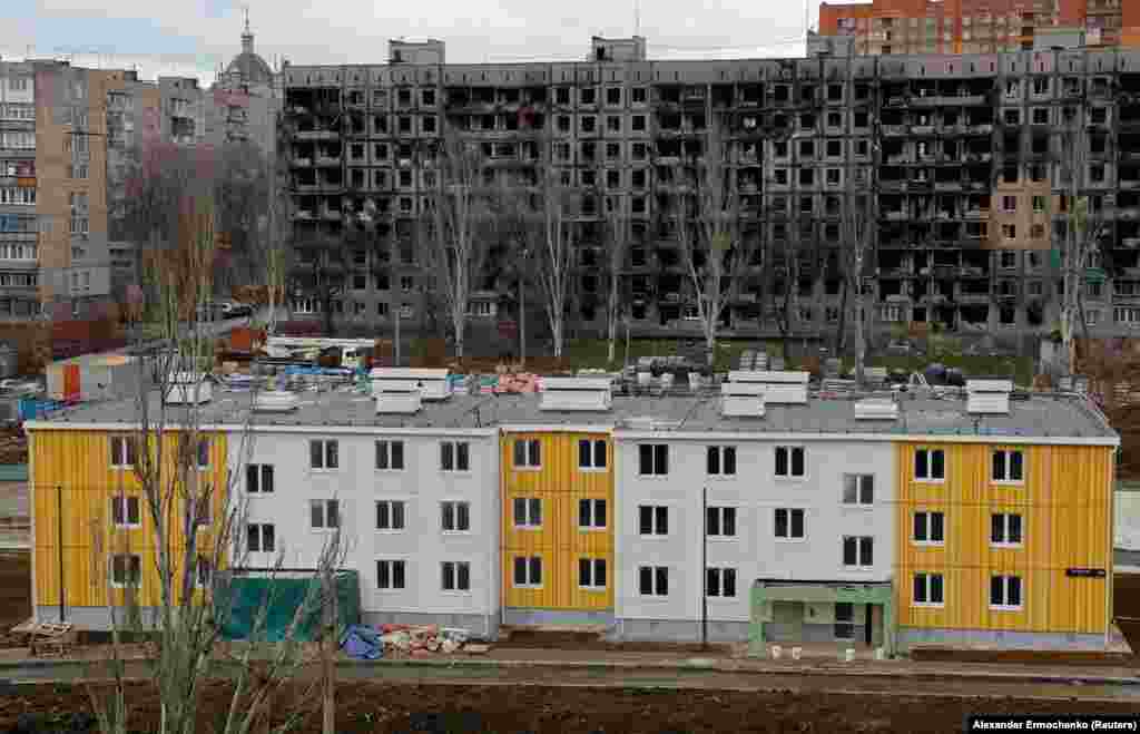 O clădire nouă construită în fața unui bloc de apartamente distrus de război. Echipa de investigație a activistului anti-Kremlin Aleksei Navalnîi susține că înalți oficiali ruși profită personal de pe urma proiectelor de reconstrucție în curs de desfășurare în Mariupol. &nbsp;