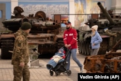 Люди біля знищеної техніки в Києві