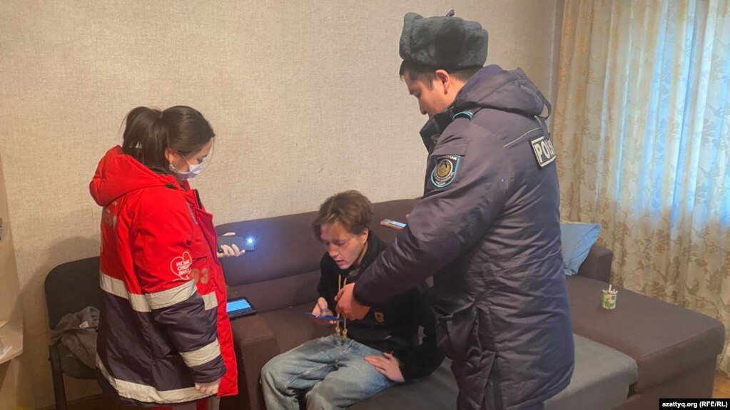 Журналист Данияр Молдабеков в окружении работницы бригады скорой помощи и полицейского, прибывших к нему после его сообщения о нападении на него. 22 февраля 2023 года