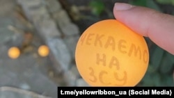 Теннисный шарик с надписью в поддержку ВСУ. Акция движения «Желтая лента» в Феодосии, август 2023 года