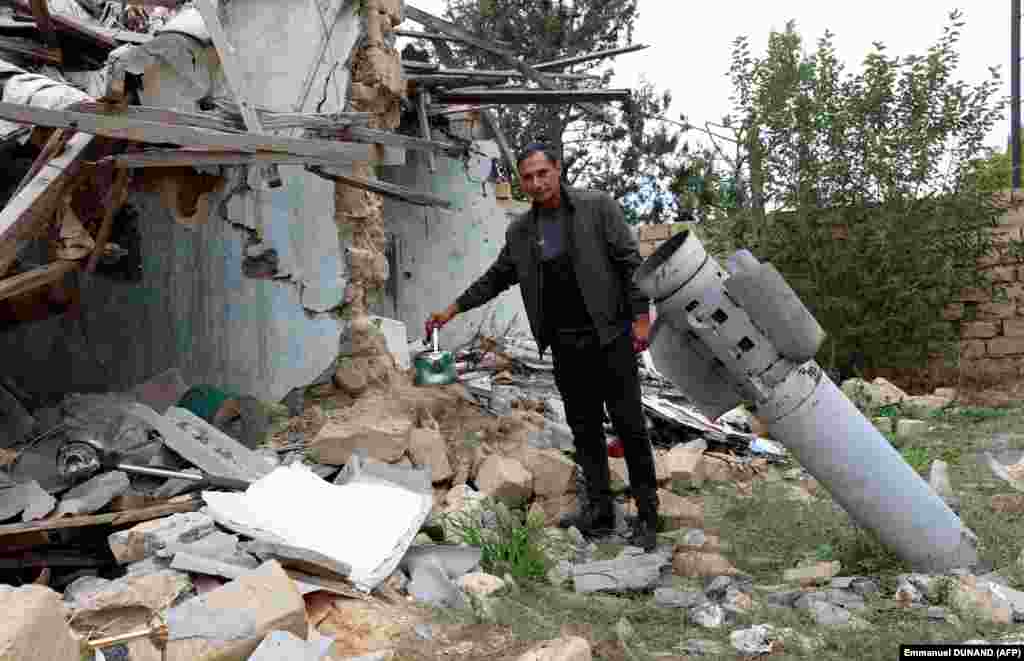 Cavid Ismayilov poses next to a missile in the ground in front of his house, which was destroyed during the 2020 war between Azerbaijan and Armenian separatists, in the town of Terter on September 24.