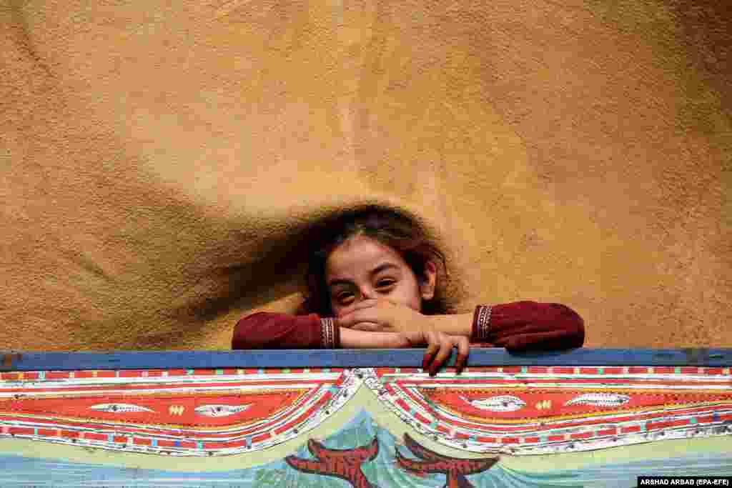 An Afghan refugee girl smiles aboard a truck while preparing to leave for her home country ahead of Pakistan&#39;s deadline for illegal immigrants to leave at the UNHCR refugee camp and repatriation center in Nowshera on October 30.