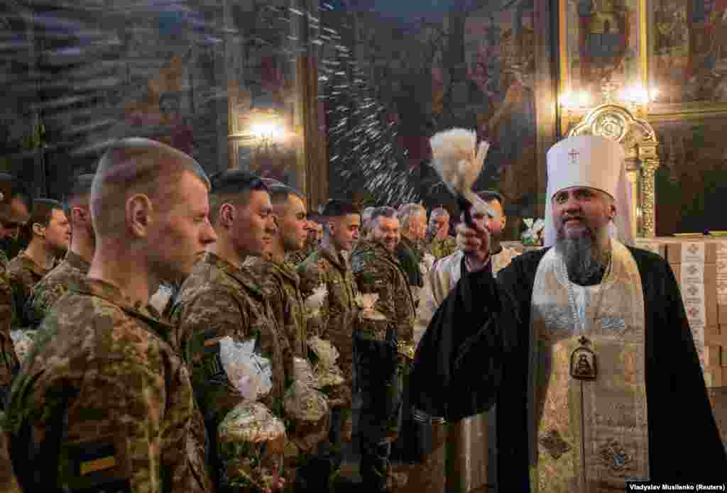 Metropolitan Epiphanius I, head of the Orthodox Church of Ukraine, sprinkles holy water on Ukrainian soldiers holding Easter cakes at St Michael&rsquo;s Cathedral in Kyiv on April 12.