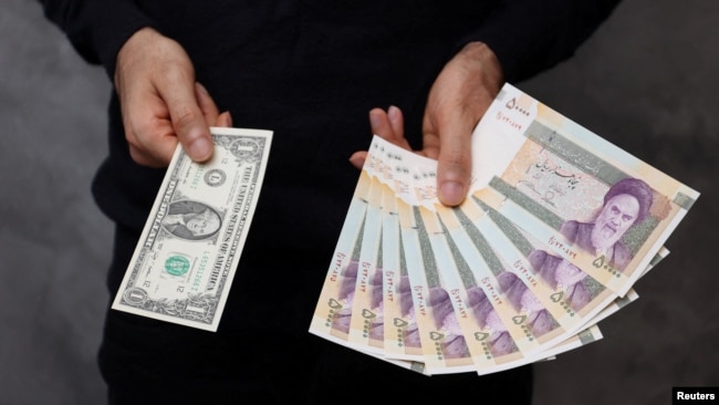 A currency dealer poses for a photo with a U.S dollar bill and the amount being given when converting it into Iranian rials in an exchange shop in Tehran in December 2022.