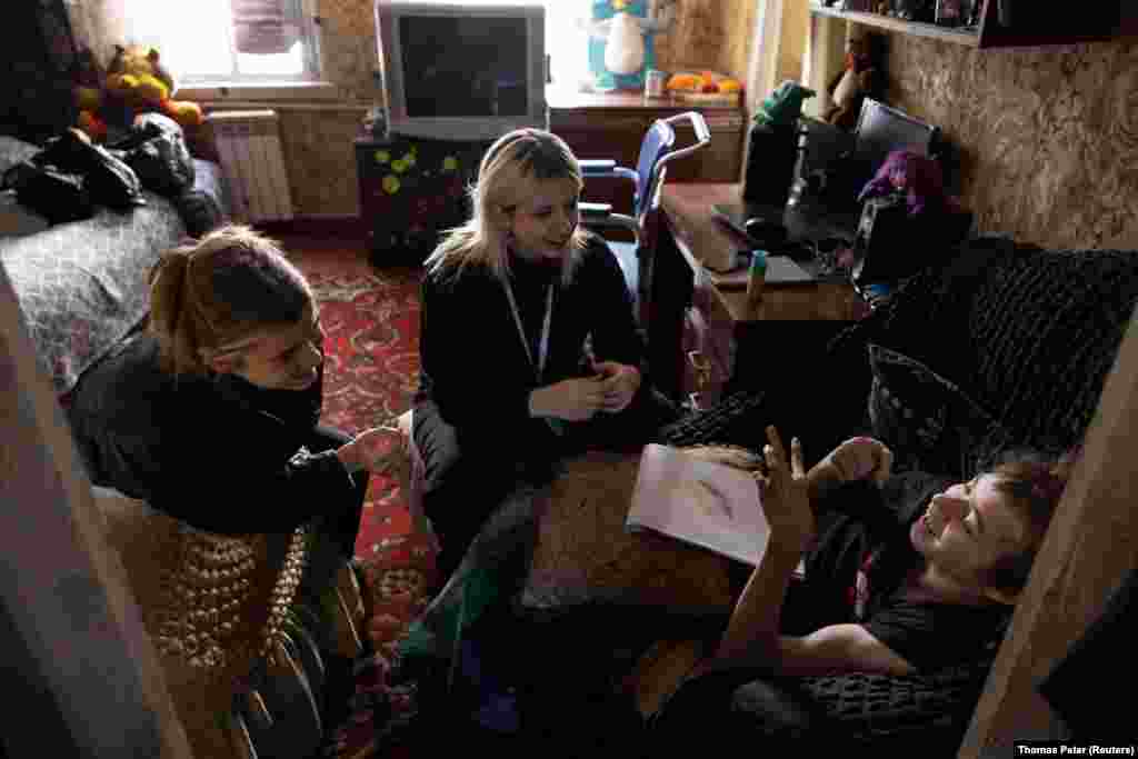 Volunteers Svitlana Korzun, 23, and Valeria Bezkluba, 28, interact with 16-year-old Ivan, who has cerebral palsy. He is one of about 500 children helped by the volunteers, whose main aim is to foster creativity and communication among children, including those with special needs.