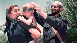 Боец за независимость Ичкерии (справа) поправляет повязку на голове ребенка. Фото: Александр Неменов