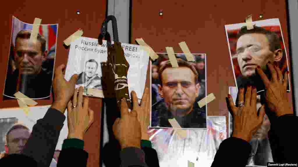 Ljudi vješaju portrete ruskog opozicionog lidera Alekseja Navaljnog na ulaznoj kapiji ruske ambasade u Kappari na Malti, dok ljudi prisustvuju protestu i bdjenju održanom nakon njegove smrti.