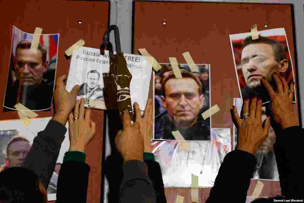People hang portraits of Russian opposition leader Aleksei Navalny at the front gate of the Russian Embassy in Kappara, Malta, as people attend a protest and vigil held following his death.