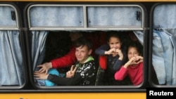 Children gesture as they are evacuated from the Russian-occupied town of Kupyansk on in the outskirts of Kharkiv in May 2022.