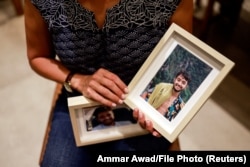Американка и израильтянка Рэйчел Голдберг, мать Херша Голдберга Полина, которого боевики ХАМАС взяли в заложники во время участия в музыкальном фестивале на юге Израиля, держит фотографии своего сына.