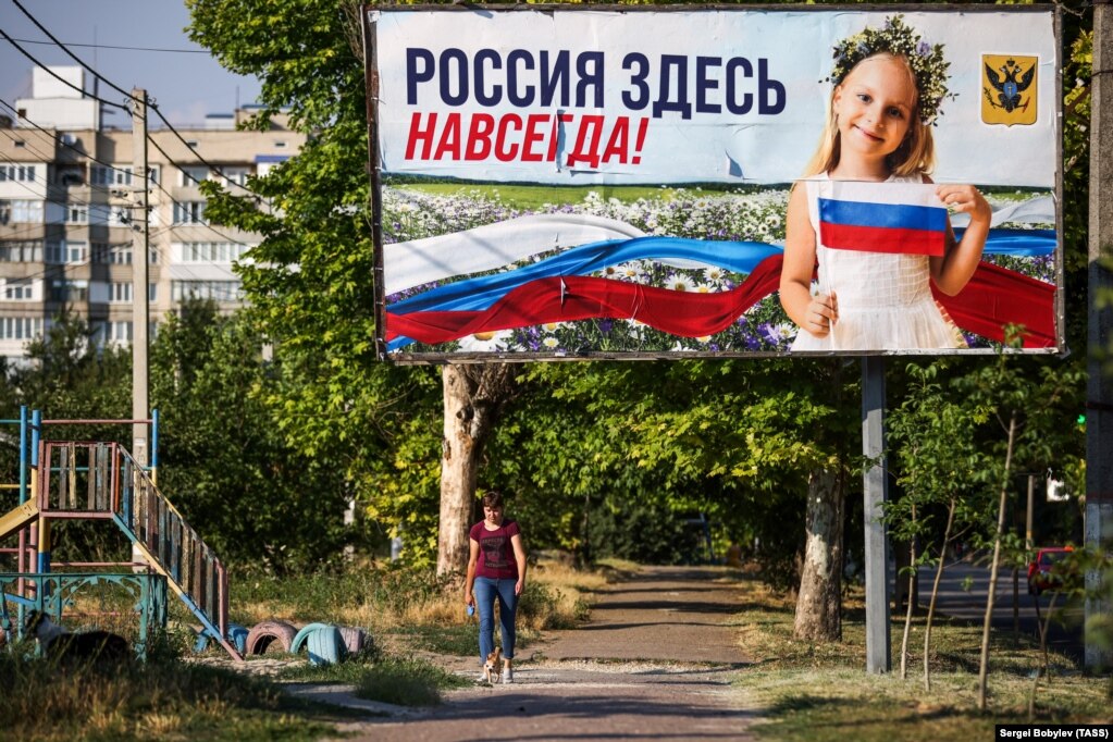 15 luglio 2022, Kherson: una donna passa davanti a un poster con il messaggio "La Russia è qui per sempre!"