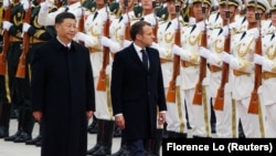 Președintele francez Emmanuel Macron (centru) și președintele chinez Xi Jinping, salută garda de onoare în timpul unei ceremonii de bun venit, în fața Marii Săli a Poporului din Beijing, noiembrie 2019.