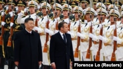 Președintele francez Emmanuel Macron (centru) trece în revistă garda de onoare, în timpul unei ceremonii de bun venit în China. Este alături de președintele chinez Xi Jinping, în fața Marii Săli a Poporului din Beijing, în noiembrie 2019.
