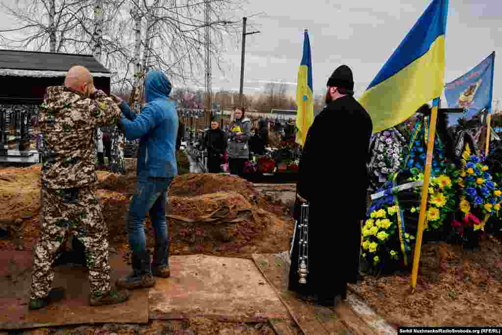 Дружина Геннадія Афанасьєва, Людмила, тримає український прапор, яким була накрита домовина під час церемонії поховання загиблого оборонця України. Київщина, грудень 2022 року&nbsp;