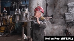 A Ukrainian power plant worker guides a detached cover to an oil pump back into place.